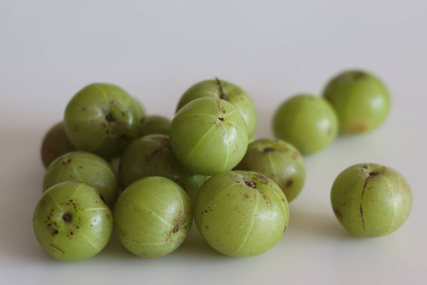 Amla or gooseberries shot on a white background. A translucent green fruit, which derives its name from the Sanskrit word Amlaki meaning nectar of life which can protect us against many ailments - Photo, Image