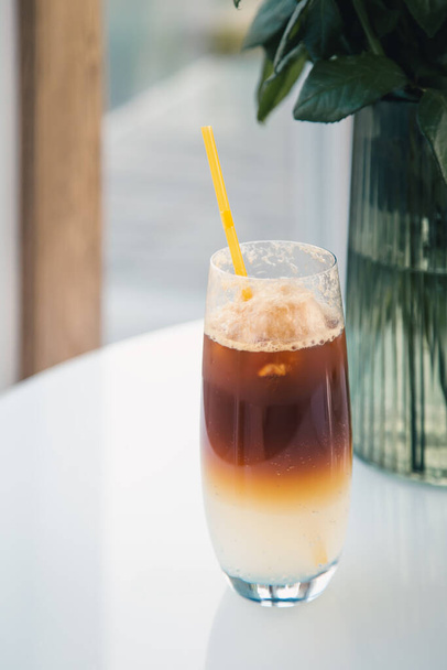Coffee cooling drink espresso tonic in a glass with a yellow drinking straw. - Foto, Imagem