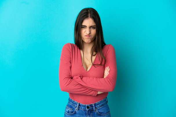 Young caucasian woman isolated on blue background with unhappy expression - Photo, Image