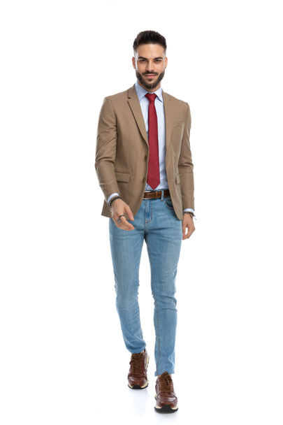 happy man with red tie and beard being sexy and walking in front of white background in studio - Photo, Image