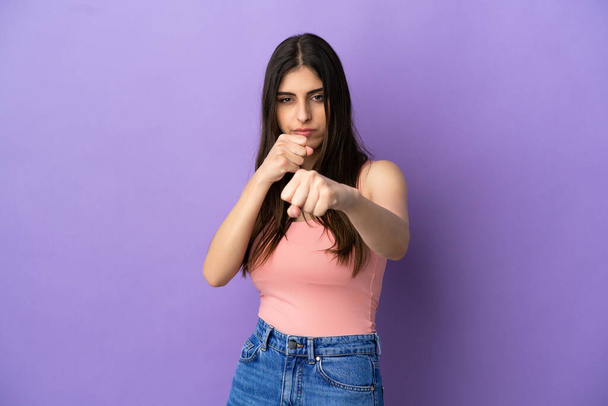 Young caucasian woman isolated on purple background with fighting gesture - Foto, Imagem