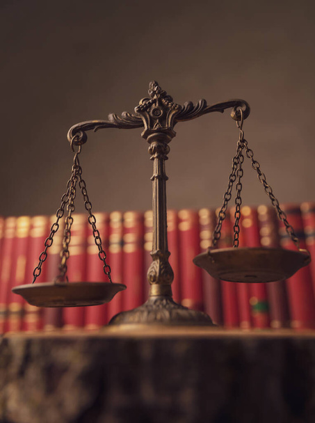 concept de justice et de droit représenté par une échelle de bronze devant une rangée de livres dans une salle universitaire - Photo, image
