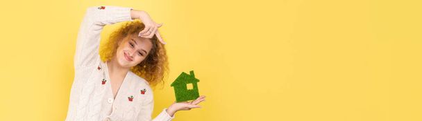 Szczęśliwego kupca. Młoda dziewczyna trzyma w rękach model zielonego domu. Koncepcja zielonej energii, ekologia. - Zdjęcie, obraz