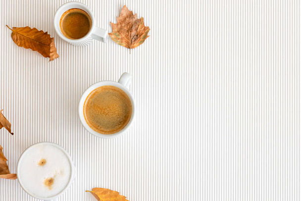 Autumn composition with cups of coffee and leaves on a textural white background, flat lay, copy space. - Foto, afbeelding