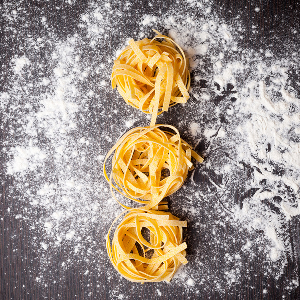 Raw pasta tagliatelle on table - Fotoğraf, Görsel