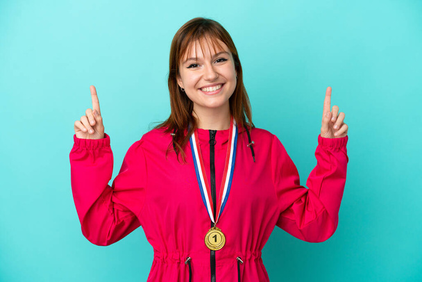 Vöröshajú lány kitüntetések elszigetelt o kék háttér rámutatva egy nagy ötlet - Fotó, kép