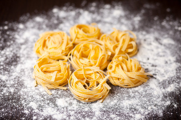 Raw pasta tagliatelle on table - Valokuva, kuva