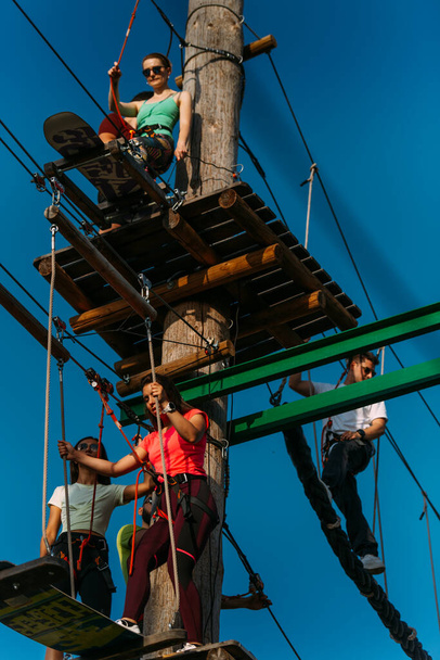 Group of skilled rock climbers waiting to go onto the next obstacle to the finish in the adventure park - Photo, Image