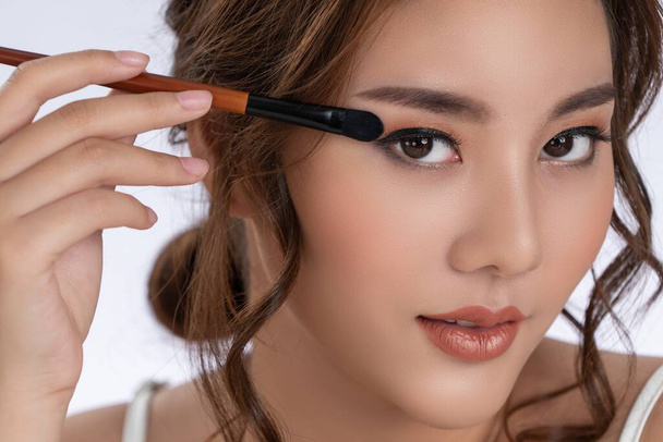 Closeup gorgeous young woman putting black mascara on her long eyelashes with brush. Beauty cosmetic concept. Female model with perfect skin. - Foto, Bild