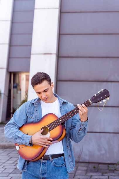 Χαριτωμένο αγόρι παίζει κιθάρα μπροστά από το κτίριο - Φωτογραφία, εικόνα