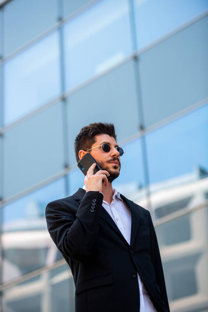 Gros plan d'un homme d'affaires parlant sur son téléphone alors qu'il se tenait devant l'effervescence - Photo, image