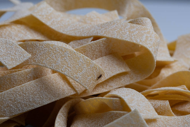 Купа неприготованих сирих італійських макаронів, жовтий фон, їжа фон, місце для вашого тексту  - Фото, зображення
