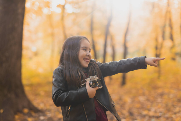 Ragazza bambino utilizzando una fotocamera vecchio stile nella natura autunno. Fotografo, stagione autunnale e concetto di svago - Foto, immagini