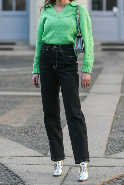 Milan, İtalya - 25 Şubat - Sokak stili, yeşil V yakalı kazak giyen kadın, Dior 'dan gümüş omuz çantası, yüksek bel siyah kot pantolon büyük pantolon, parlak topuklu ayakkabı. - Fotoğraf, Görsel