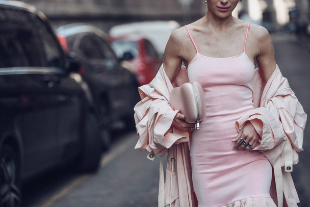 Street style, woman wearing a pale pink tank-top tube knees with embroidered pale pink midi dress, a pale pink oversized long trench coatand pink strappy sandals. - Photo, Image