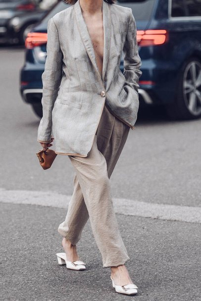Milan, Italy - February, 24: Street style, woman wearing silver blazer jacket, beige large pants, a brown shiny leather micro First handbag from Fendi, white leather with large silver buckle heels. - Foto, Imagen