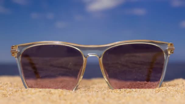 Een opeenvolging van veranderende zonnebrillen op het strand met passerende wolken  - Video