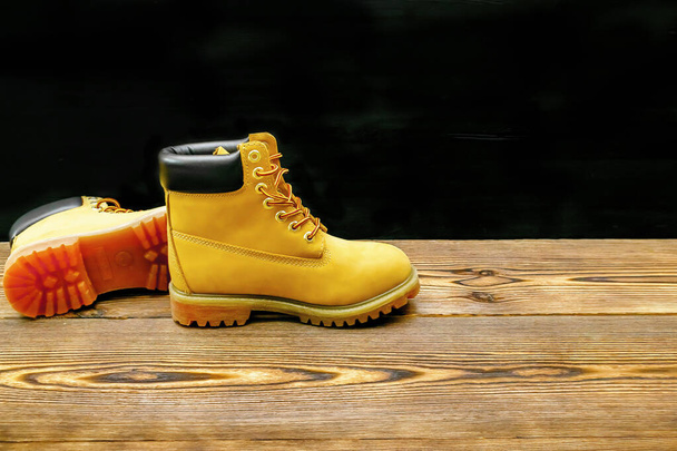 Нові красиві коричнево-жовті теплі гірські жіночі зимові туфлі Timberland, черевики, кросівки, тренери логотип на дерев'яному фоні. Концепція спортивного повсякденного взуття
. - Фото, зображення