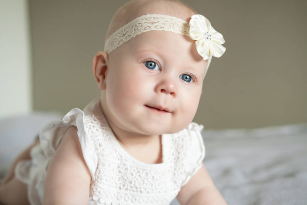 美しい小さな赤ん坊の少女の肖像画は、彼女の胃の上に横たわると感心して離れて見ています。大きな青い目の赤ちゃん。幸せな家族の概念 - 写真・画像