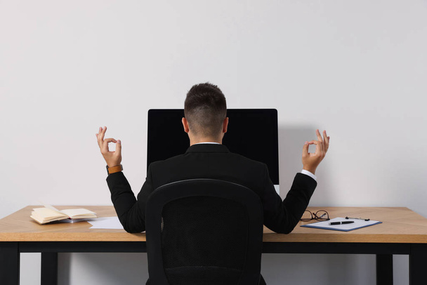 Businessman meditating at workplace, back view. Zen concept - Foto, Imagem