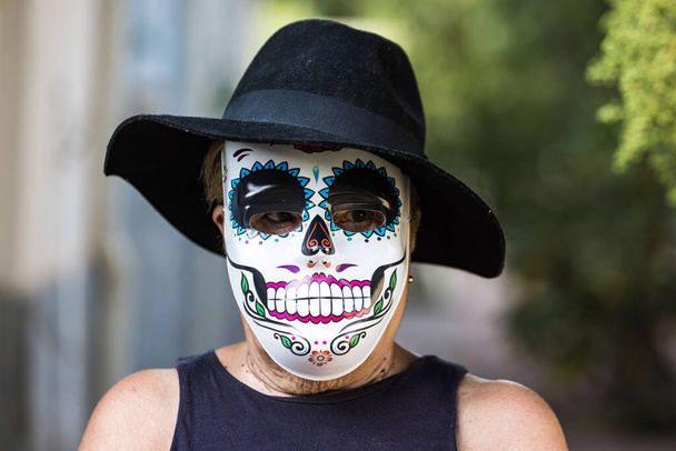 Portret starszej pani w masce katriny i kapeluszu, świętującej Halloween i Dzień Wszystkich Dusz na ulicy. Celebracja, kostium, strona i koncepcja maski. - Zdjęcie, obraz