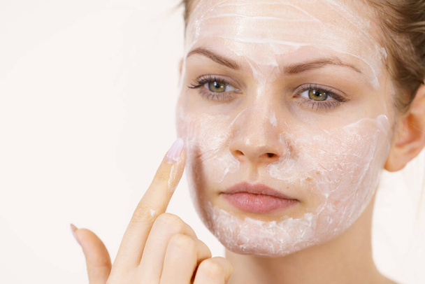 Young woman applying cream cosmetic, mask moisturizing to her face. Beauty treatment. Skincare. - Фото, изображение