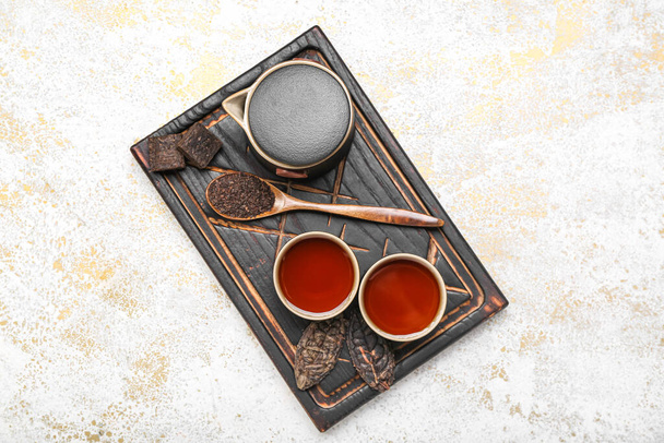 Доска с чашками чистого чая, ложки и чайник на фоне гранж - Фото, изображение