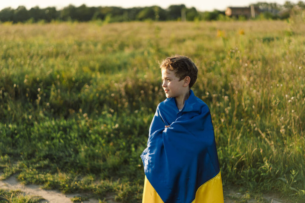 Ukraines Independence Day. Ukrainian child boy in white t shirt with yellow and blue flag of Ukraine in field. Flag of Ukraine. Constitution day. Stand with Ukraine and Save - Fotoğraf, Görsel