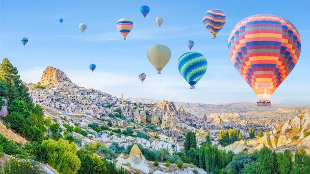 panoramic landscape scenery of hot air balloons over Goreme town in Cappadocia region Turkey with blue sky background - Foto, Bild