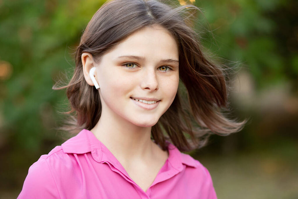 Piękna młoda dziewczyna cieszyć się słuchanie muzyki z bezprzewodowym słuchawki z dobrym nastroju i relaks na świeżym powietrzu.  - Zdjęcie, obraz