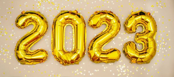 2023 golden foil balloons numbers,  stars confetti, ribbons and bokeh. Top horizontal view copy space new year and holiday concept. - Fotografie, Obrázek