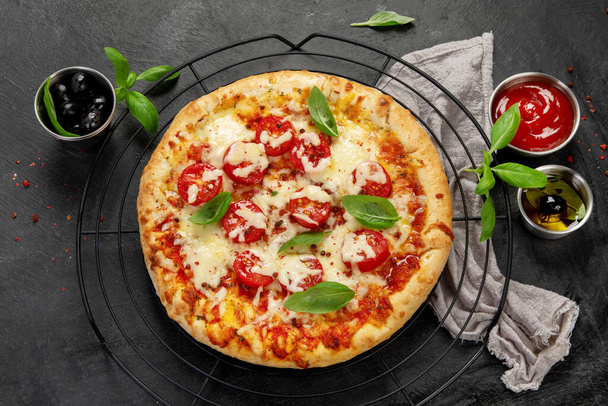 Freshly baked pizza on dark background. Tasty homemade food concept. Top view - Photo, image