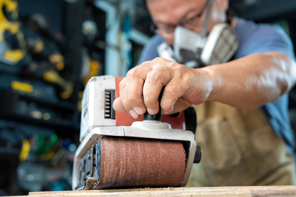 carpinteiro trabalhando com lixadeira de cinto de polimento em madeira na oficina, fabricante de bricolage e conceito de madeira. foco seletivo - Foto, Imagem