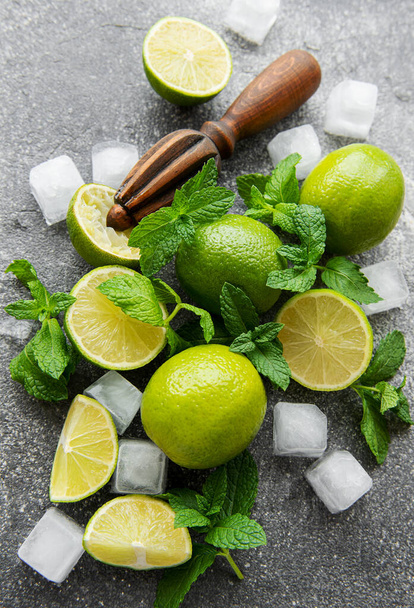 Lime, mint and ice on a dark background. The ingredients for making refreshing drinks and cocktails. - Photo, image