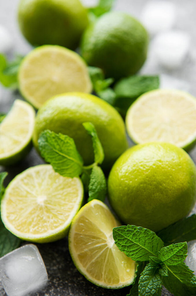 Lime and mint on a dark background. The ingredients for making refreshing drinks and cocktails. - Фото, изображение