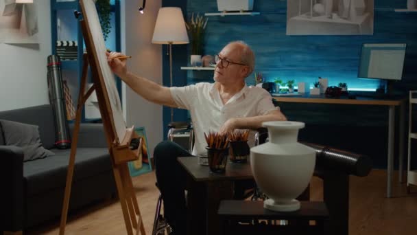 Old man with physical disability using artistic tools to draw vase design at home, having imagination hobby. Wheelchair user with impairment drawing artwork masterpiece sketch. - Footage, Video