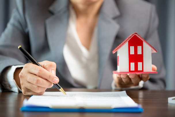 Woman home sales person is checking documents for house purchase contract before letting the customer sign contract on table is key with house model, real estate trading and insurance property concept - Valokuva, kuva