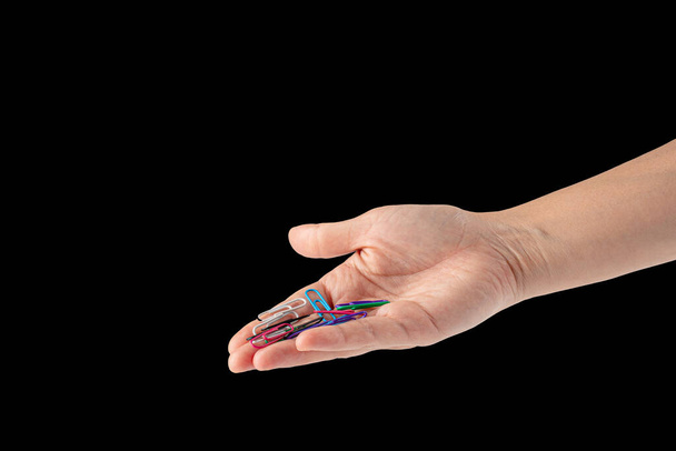 Hand and colorful paper clips isolated on black background - Photo, image