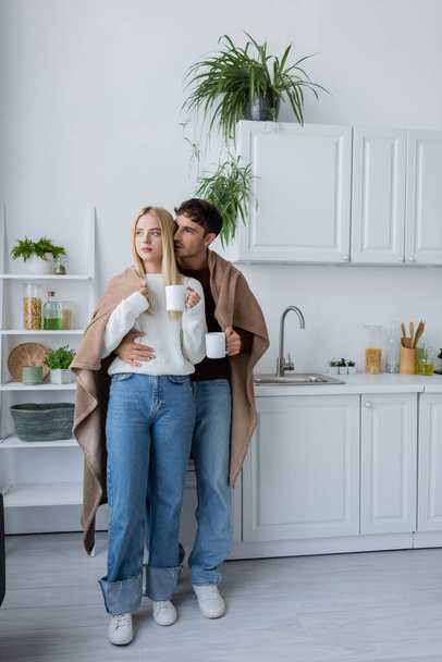 fiatal pár borított takaró ölelés és gazdaság csésze tea - Fotó, kép