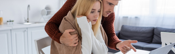 Mann im Pullover zeigt auf Laptop neben junger Freundin im Pullover, Transparent - Foto, Bild
