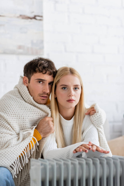 giovane coppia coperta di riscaldamento coperta vicino moderno radiatore a casa - Foto, immagini