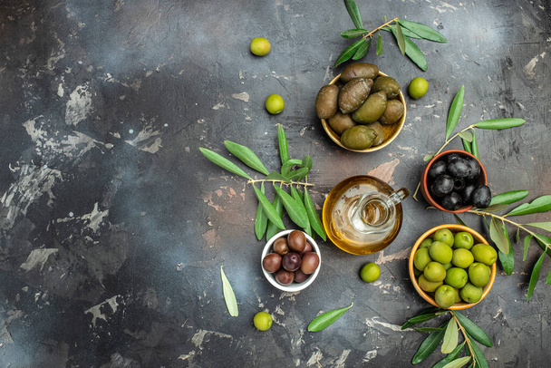 Different types of olives in olive bowls and olive oil on a dark background, Olive concept, banner, menu, recipe place for text, top view, - Zdjęcie, obraz