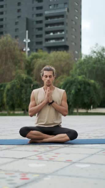 Der Mensch meditiert und bewegt sich zur Seite, während er im Freien auf einer Yogamatte sitzt. Wellness und gesunder Lebensstil. - Filmmaterial, Video