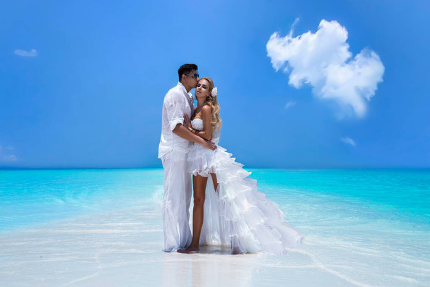 Letní láska. Krásný šťastný mladý pár ve svatebním oblečení stojí na pláži na Maledivách. Zasnoubení a svatba na pláži na ráji ostrova Maledivy. Luxusní cestování. - Fotografie, Obrázek
