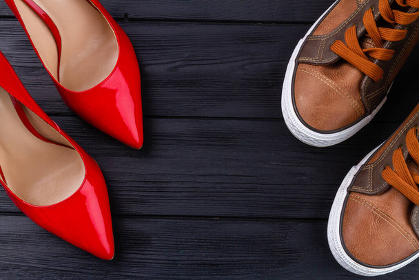 Мужские туфли и красные женские туфли на высоком каблуке. Темный деревянный фон. Копирование текста. - Фото, изображение