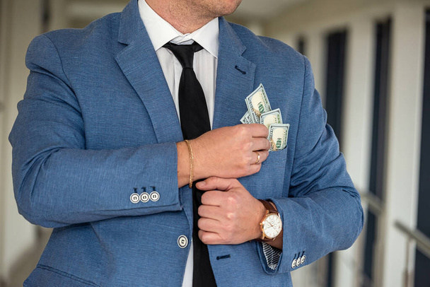 a large and very large sum of dollars from a handsome man in a stylish suit. Big business concept - Foto, Bild