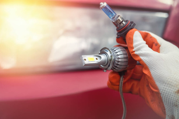 Homens de serviço de carro segurar uma lâmpada de halogéneo para reparar ou mudar um farol. Conceito de reparação automóvel. Um homem muda uma lâmpada - Foto, Imagem