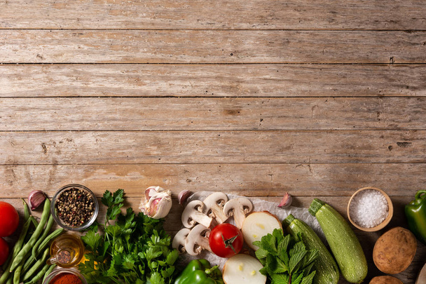 Assortment of vegetables, herbs and spices on wooden table. Top view. Copy space - 写真・画像