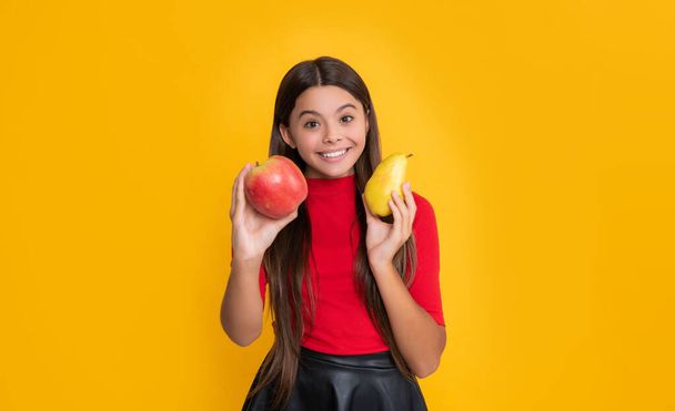 happy kid hold fresh apple and pear on yellow background. - Valokuva, kuva