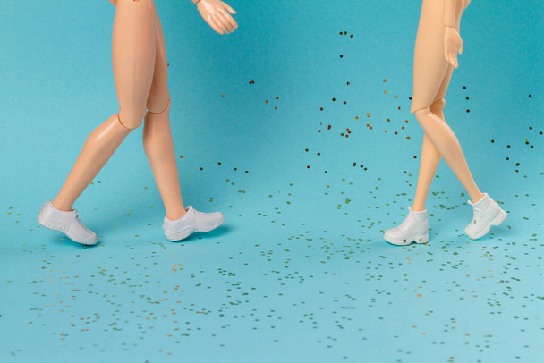 Walking toy doll mothers and daughter legs. Glitters on blue background. - 写真・画像